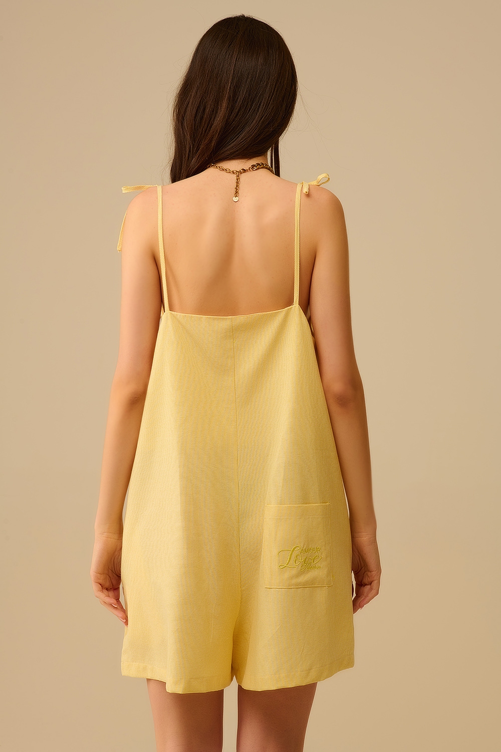 Mono amarillo a rayas con lazos en los hombros y bolsillo trasero