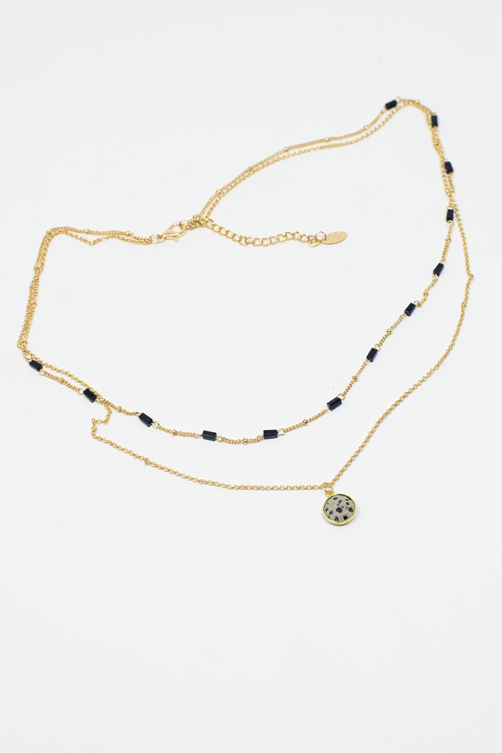 Collar corto 2 en 1 de oro con cuentas negras y piedra jaspeada blanca.