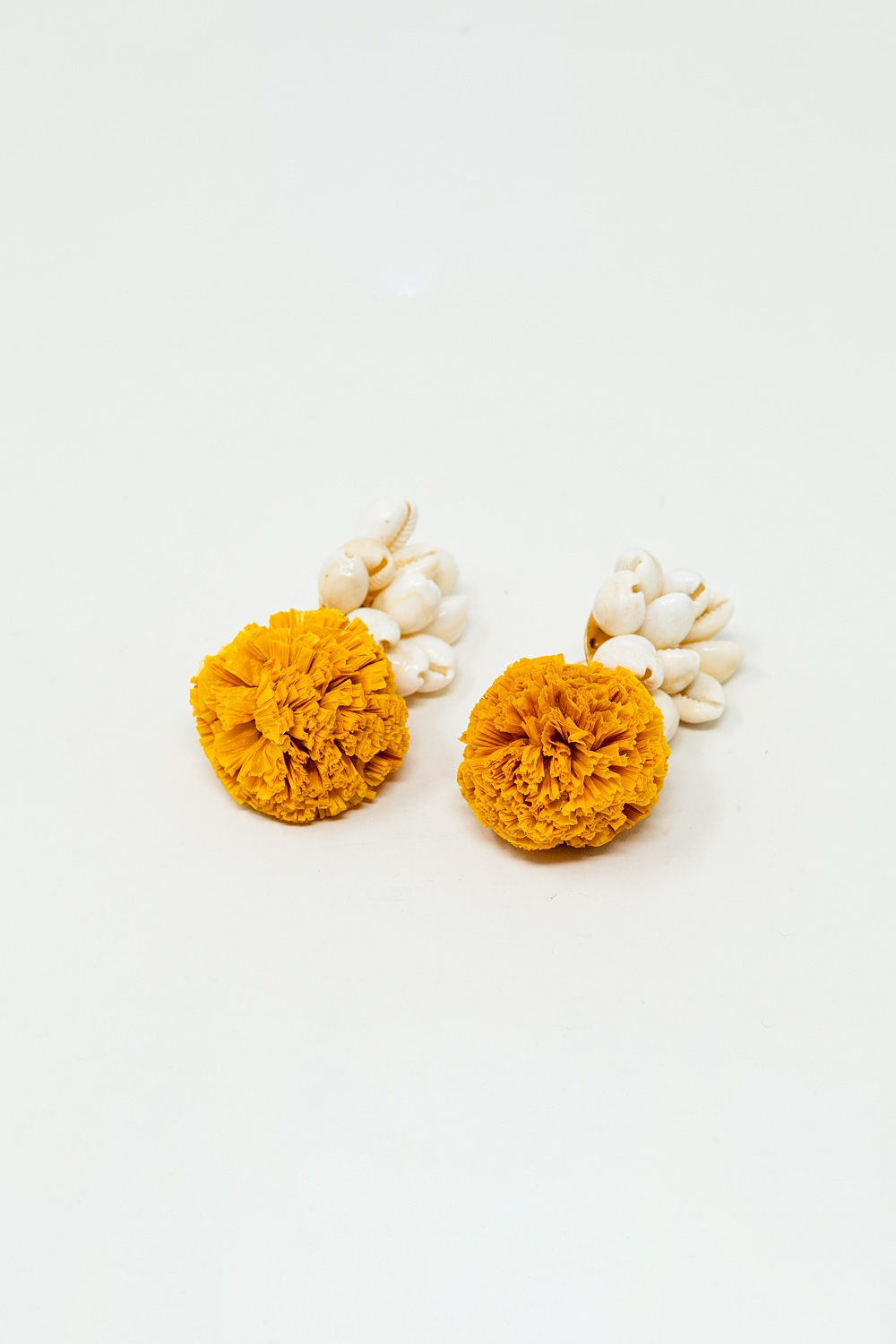 Pendientes con conchas de mar color crema y pompones amarillos