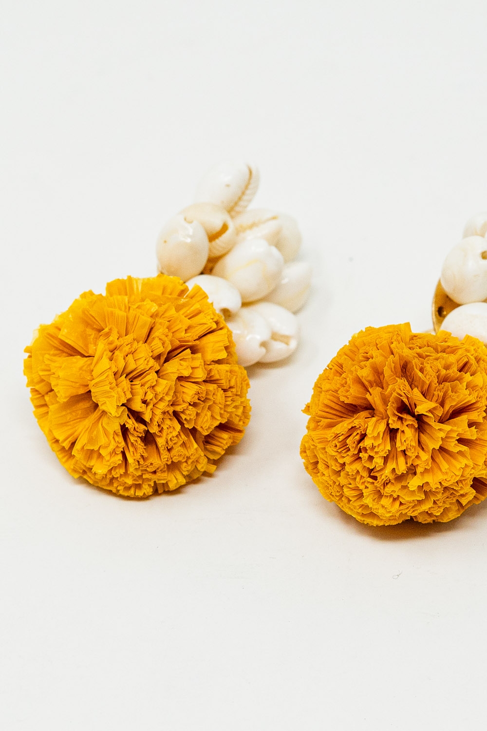 Pendientes con conchas de mar color crema y pompones amarillos